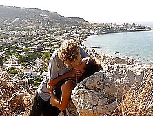 Beautiful Teen Couple In Love Passionately Kissing Above The Sea On Crete Island
