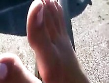 Chick Teasing Her Feet At A Parking Lot